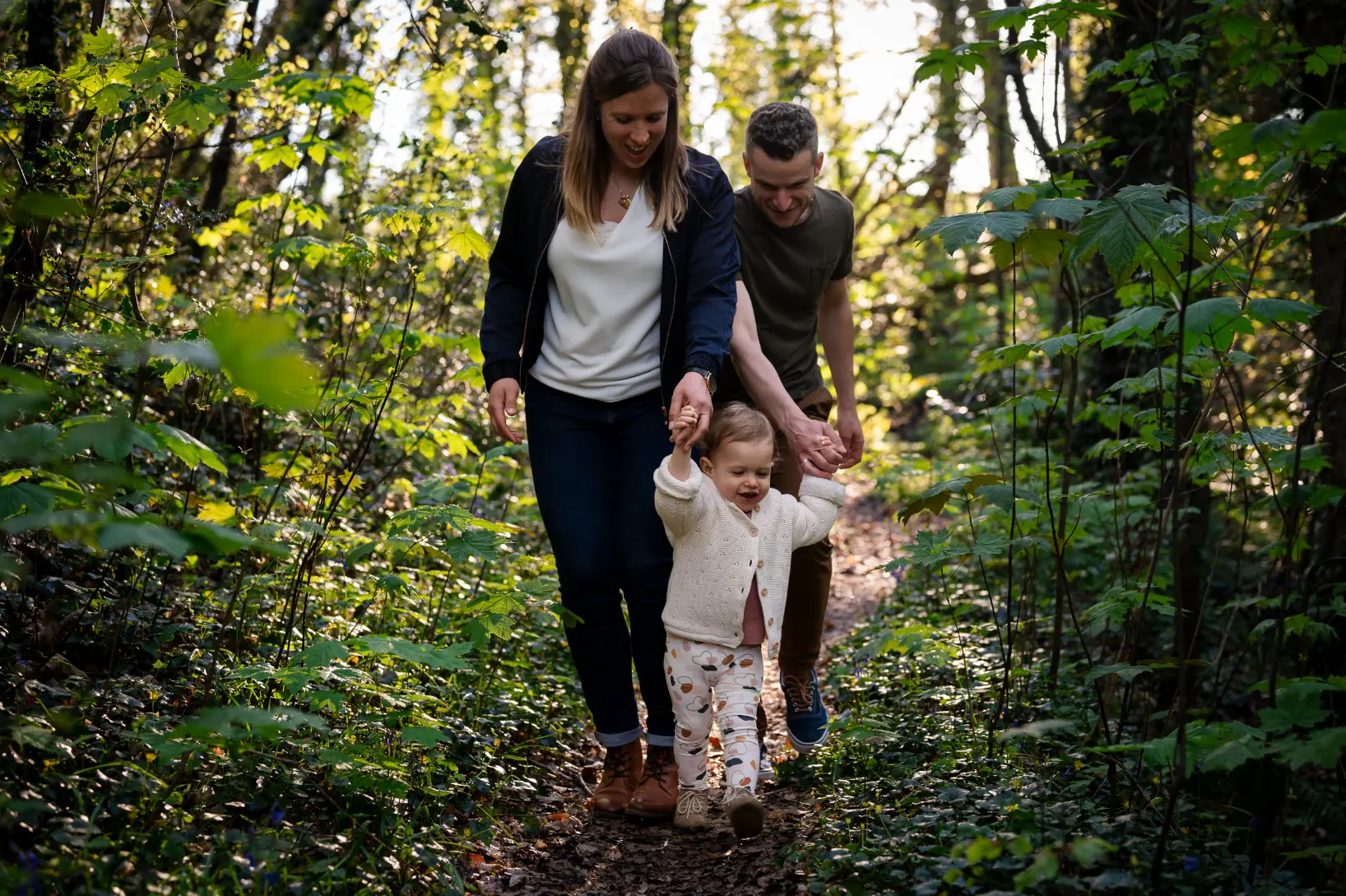 des parents se baladent avec leur fille d'un an en forêt