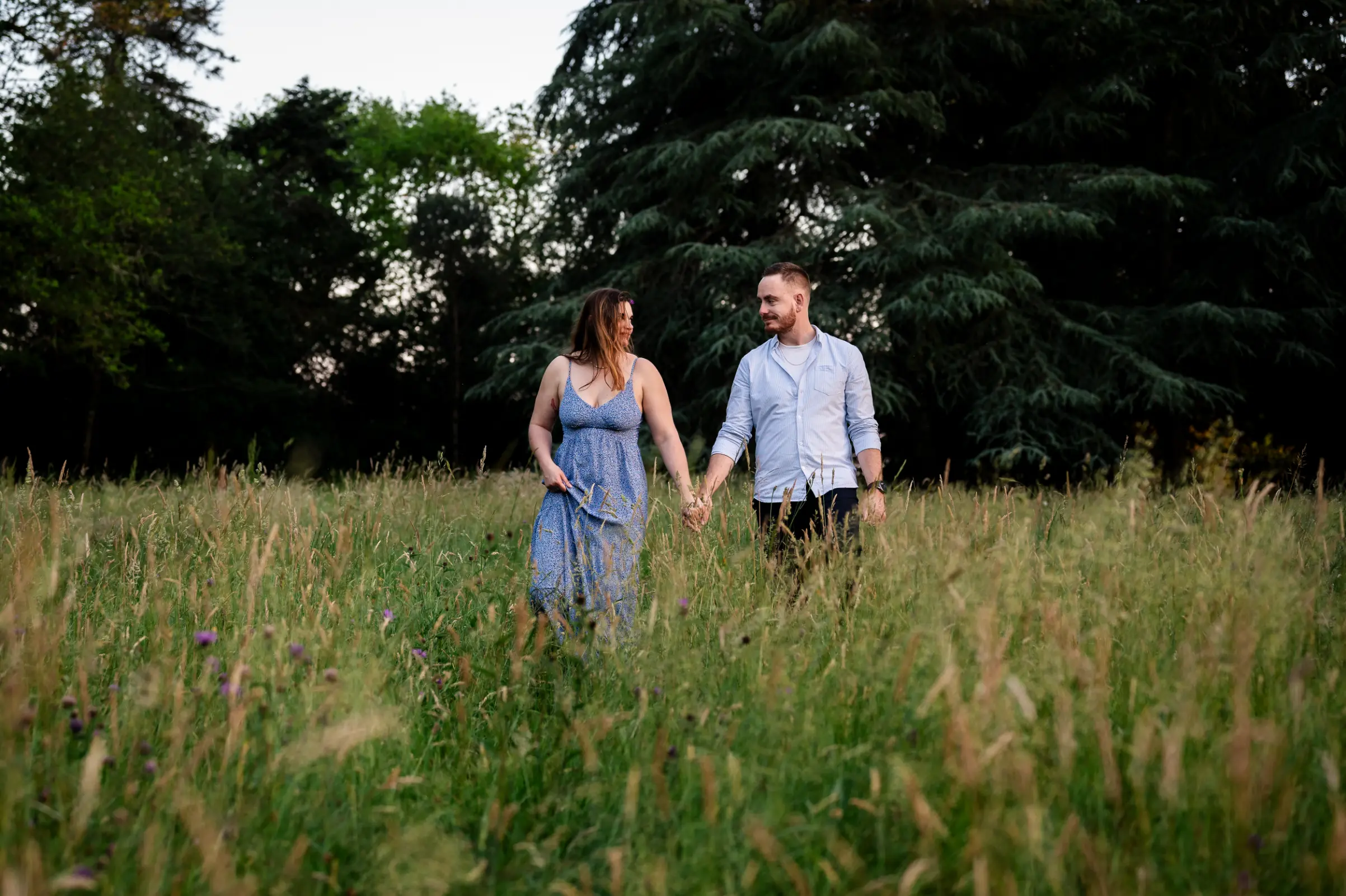 un couple de futurs mariés, profite de cette séance couple pour appréhender l'appareil photo, la scène se passe dans les hautes herbes, en fin de journée au parc de la chantrerie, sous un lumière orangée