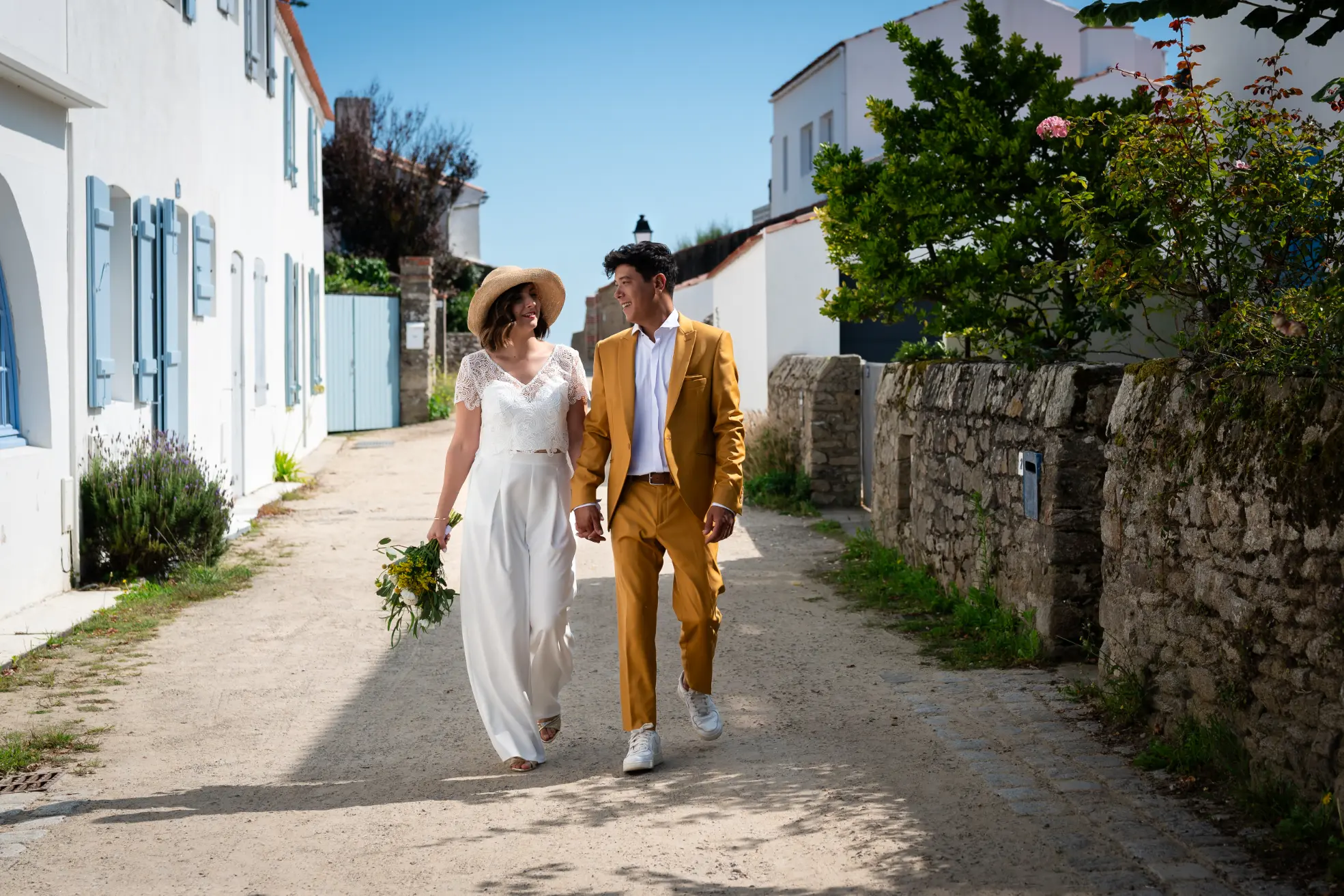 mariés marcha dans une rue du village du grand viel. de chaque côté de la rue, des maison blaches typique s de noirmoutier 