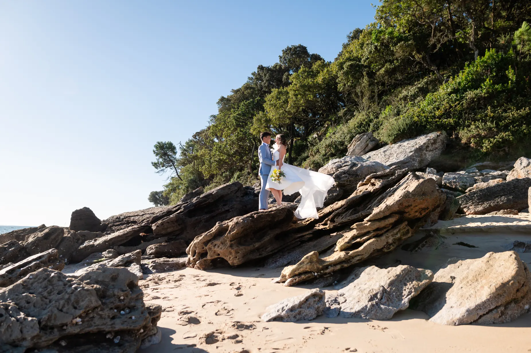 couple de mariés lors d'une séance photo de couple su les rochers de la plage de l'anse rouge à noirmoutier