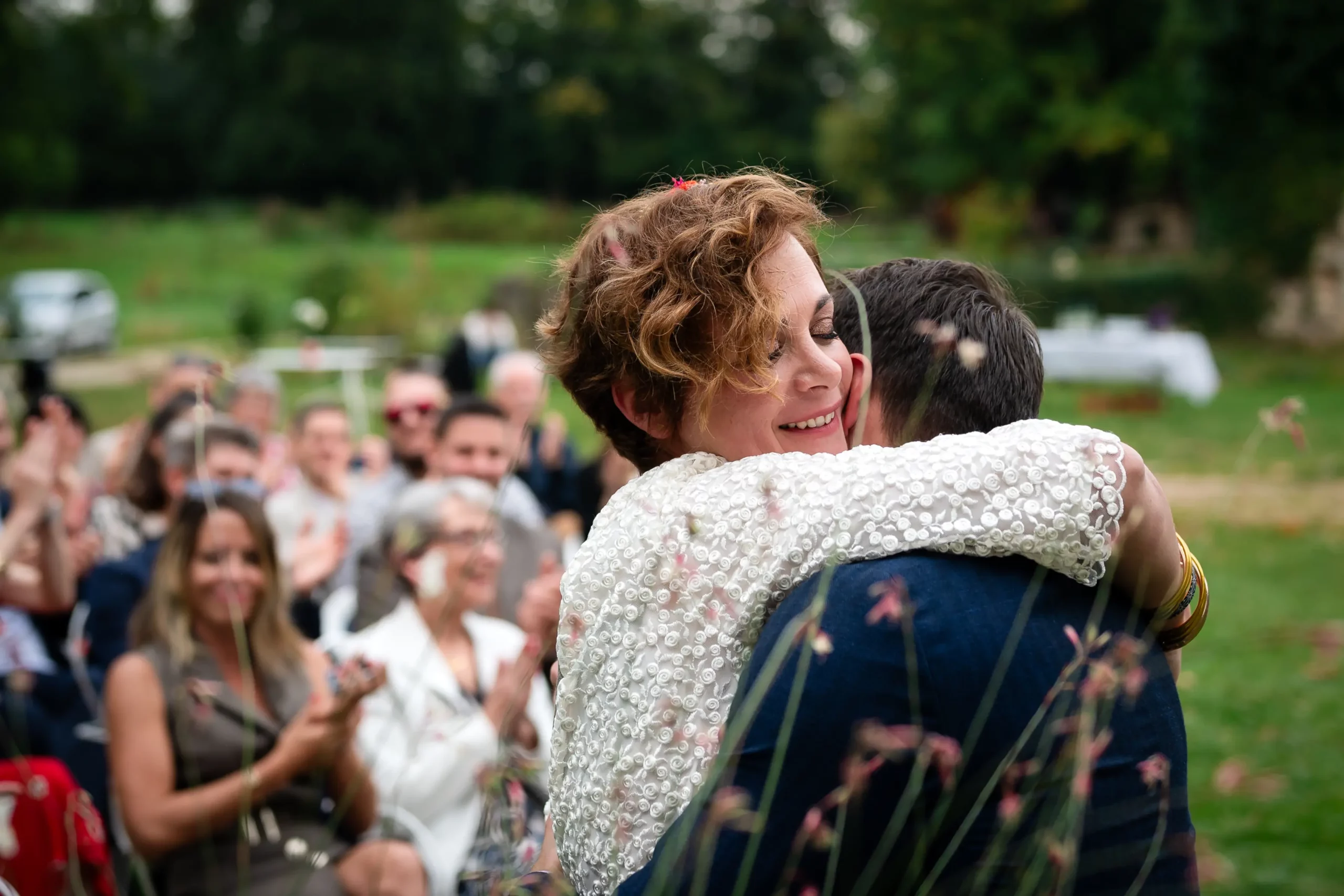 la mariée embrasse son époux à la fin de la cérémonie laïque du mariage, en arrière plan les invités applaudissent